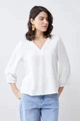 Blusa color crudo con escote en V y mangas largas.
