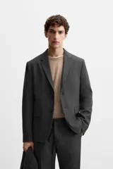 Blazer slim fit color gris oscuro confeccionado en tejido con viscosa. Tiene cuello con solapas de muesca, manga larga con puño abotonado, bolsillo de vivo en pecho, bolsillos de solapa en cadera, bolsillo interior, bajo con aberturas en espalda y cierre frontal con botones.