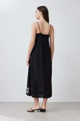 Maxi vestido negro de breteles finos con escote recto y bordado floral en el ruedo.