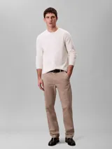 Pantalón chino de corte slim color beige, confeccionado en algodón y elastano. Presenta cierre con cremallera y botón, diseño clásico de cuatro bolsillos y logo de Calvin Klein bordado en la parte posterior.