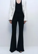 Pantalón negro de vestir, tiro medio, corte wide leg y aberturas laterales en el ruedo.