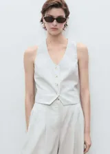 Chaleco de vestir a rayas verticales color crudo y blanco, con cuello en V, sin mangas y cierre frontal con botones.