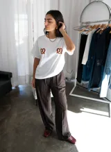 Pantalón sastrero de vestir color chocolate con finas rayas verticales blancas, de tiro alto y corte recto. Cuenta con bolsillos laterales y pretina trasera elastizada.