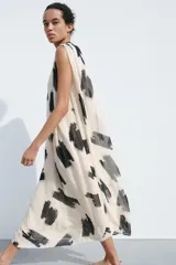 Vestido midi de Zara Woman Collection confeccionado en hilatura de viscosa color crudo con estampado abstracto en negro. Tiene cuello redondo, manga sisa, tejido plisado, forro interior y cierre en la espalda.