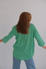 Blusa verde a rayas verticales blancas, con escote en V y mangas 3/4.