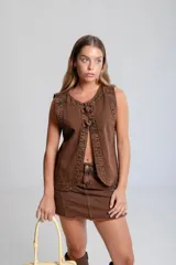 Chaleco de denim negro sin mangas con cuello redondo y costuras en contraste. Presenta un parche de cuero marrón en la parte posterior con el logo de la marca Be Ganesha. Confeccionado en tejido de algodón.