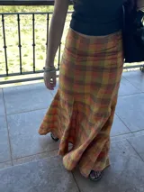Falda larga de lino con estampado escocés en tonos otoñales (naranja, amarillo, marrón y rojizo). Diseño con gajos que le otorgan mucho movimiento, ajustada en la cadera y con vuelo en el ruedo (corte sirena o trompeta).