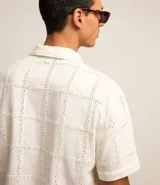 Camisa de manga corta color crema con textura cuadriculada con lesie, cuello inglés y abotonado delantero.