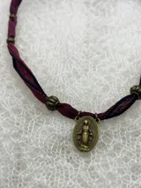 Collar artesanal con cintas de seda color borgoña y azul marino, cuentas metálicas color bronce y dije ovalado de la Virgen Milagrosa.