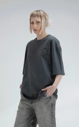 Remera negra de corte holgado con estampado de calaveras y cruz en el frente.