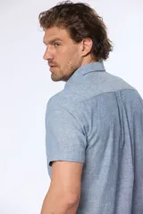 Camisa celeste de lino y algodón, de manga corta, con cuello abotonado y bolsillo en el pecho.