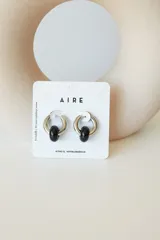 Aros de acero quirúrgico hipoalergénico con forma de argolla plateada y dije circular colgante de piedra natural color azul.