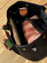 Bolso negro tipo tote de neopreno con bolsillo interno de red, sobre haciendo juego y gancho para sujetarlo.