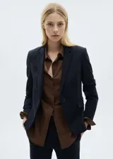 Blazer azul marino con cuello de pico con solapa, cierre de botón en la parte delantera, manga larga con puños abotonados, diseño recto y dos bolsillos de solapa en la parte delantera.