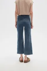 Pantalón jean blanco, recto y de calce alto con terminación desflecada.