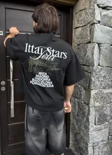Remera celeste con estampa de paisaje costero y texto "Ittai Stars" y nombres de ciudades.