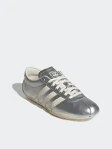 Zapatillas Adidas Tokyo color plateado con las tres tiras laterales en color crema.