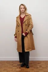 Trench coat largo color beige con doble botonadura, cuello solapa, cinturón ajustable y puños con tiras.