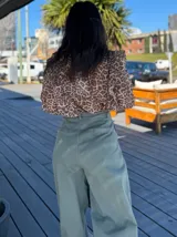 Pantalón de jean celeste de corte ancho con pinzas en la cintura y cinturón plateado con apliques florales.