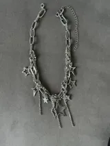 Collar plateado de eslabones gruesos y cadenas finas con dijes de estrellas de diferentes tamaños y colgantes de strass.