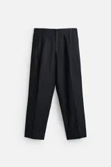 Pantalón de denim azul oscuro, corte wide fit, largo cropped, con pliegues frontales, bolsillos laterales y traseros asimétricos. Cierre frontal con cremallera y gancho metálico oculto.