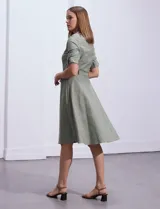 Vestido camisero blanco de algodón con cuello con solapa, delantera abotonada, mangas 3/4 regulables con presilla y botón, y cintura con lazo de ajuste.