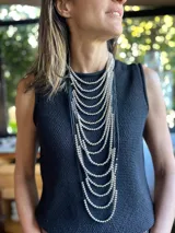 Collar largo de múltiples hilos con cuentas plateadas y cordones negros.