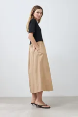 Vestido midi de corte recto, con top negro de mangas cortas y falda color beige.