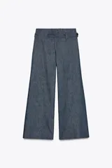 Pantalón de tiro medio azul denim, con trabillas en la cintura y cinturón ajustable con botones. Tiene bolsillos laterales ocultos y pierna ancha.