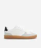 Championes urbanos de corte bajo, color blanco con detalles en gris y negro. Confeccionados en material sintético con recortes efecto gamuza y suela de látex color caramelo.