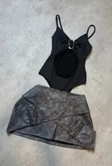 Body negro con escote halter, abertura en el abdomen y detalle metálico en el centro.