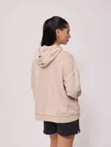 Canguro gris con capucha corta, bolsillo tipo canguro y parche con logo de la marca Rusty en el pecho. Tiene efecto lavado y costuras a la vista.