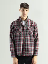 Camisa de franela a cuadros rojos, negros y grises, de manga larga y corte clásico, con dos bolsillos en el pecho.