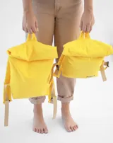 Mochila amarilla de tela con tiras de cuero color beige.