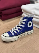 Zapatillas de lona blancas de caña alta con cordones y puntera de goma. Logo de durazno engomado en la base y en la cara interna.