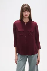 Camisa holgada de viscosa, color vino tinto, con cuello mao, manga 3/4 con presilla y dos bolsillos frontales con tapa.