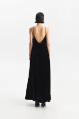 Vestido largo negro de tirantes finos, con escote recto en el frente y escote en V en la espalda. Presenta un calce holgado y bolsillos laterales.