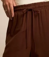 Pantalón pantalona marrón de viscolino, con cintura elástica, bolsillos laterales y lazo ajustable en la cintura.