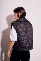 Chaleco negro acolchado con cierre frontal y cuello alto. Diseño reversible con cordones ajustables en la cintura.