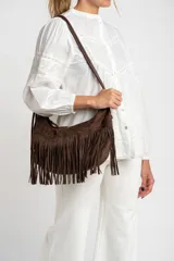 Cartera bandolera marrón con flecos largos en la parte delantera y correa fina al hombro.
