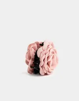 Broche con forma de flor de tela color rosa claro con gancho metálico negro.