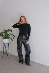 Pantalón negro de cuero sintético, corte palazzo y tiro alto.