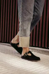 Zuecos marrones de cuero con hebilla dorada ajustable.