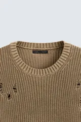 Sweater color marrón claro de punto con cuello redondo y manga larga. Presenta roturas en toda la prenda y terminaciones irregulares.