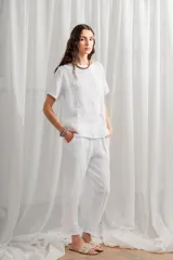 Blusa blanca de lino, corte holgado, con cuello redondo y cierre frontal con botones.