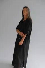 Camisola larga negra de lino italiano, con corte fluido, cuello camisero, mangas 3/4 con botón y abertura lateral en el ruedo.