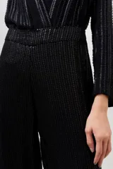 Pantalón palazzo negro con lentejuelas y mostacillas bordadas, tiro medio y cierre lateral invisible.