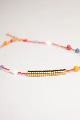 Gargantilla de hilo rojo con cuentas de colores y dije central de cilindro dorado.