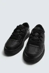 Zapatilla deportiva negra de estilo retro con suela de goma con volumen.