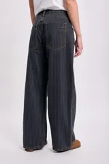 Pantalón de jean negro con rayas verticales blancas, corte recto y tiro alto.